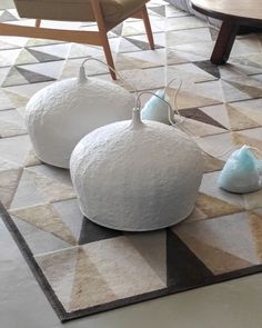 three white vases sitting on top of a rug