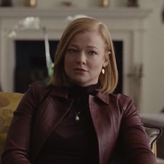 a woman sitting in a chair wearing a leather jacket