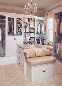 a walk in closet filled with lots of clothes and drawers next to a chandelier