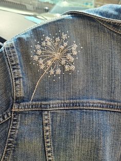 an embroidered dandelion on the back of a jean jacket