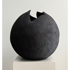 a black sculpture sitting on top of a white pedestal