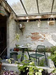 two green chairs sitting on top of a patio next to a table and potted plants