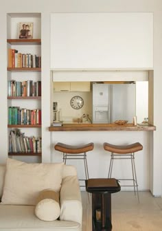 a living room filled with furniture and bookshelves next to a kitchen counter top