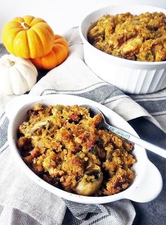 two white bowls filled with food on top of a table next to pumpkins and a towel