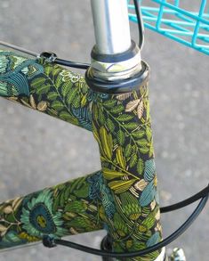 a close up view of the handlebars on a green and blue bicycle with flowers