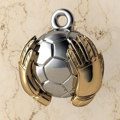 a silver and gold gloved hand holding a soccer ball on a marble wall background