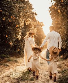 a man and woman holding hands while walking down a dirt road with two small children