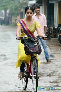 a woman riding a bike down a rain soaked street