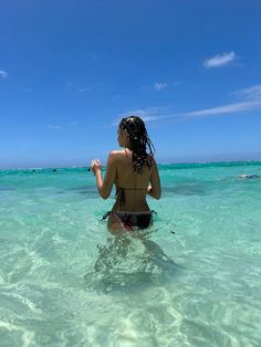 a woman standing in the ocean with her back to the camera