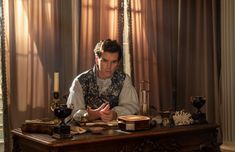 a man sitting at a desk in front of a candle and some other things on the table