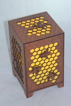 an intricately designed wooden box with honeycombs and bees on the sides, sitting on a white surface