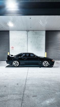 a black car parked in front of a garage door with no doors on it's sides