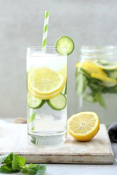 a glass filled with lemonade and cucumber on top of a cutting board