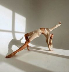 a woman is doing a handstand on the floor with her legs spread out