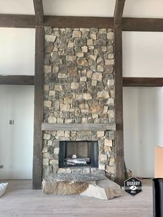 a living room with a stone fireplace and wooden beams