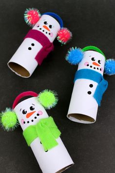 three snowmen made out of toilet paper tubes with pom - poms on them