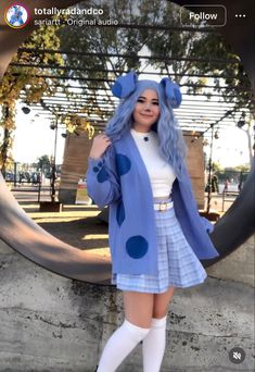 a woman with blue hair is posing in front of a sculpture and wearing a costume