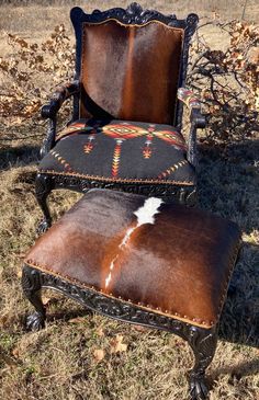 an old chair and ottoman are sitting in the grass with a cow hide on it