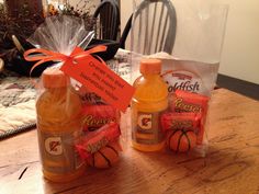 two bottles of orange juice sitting on top of a wooden table next to a bag