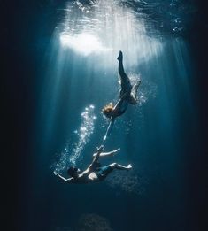 two people are swimming in the ocean with their backs to each other and one person is diving