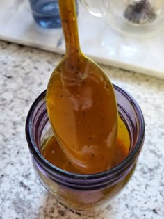 a glass jar filled with sauce sitting on top of a counter next to a spoon