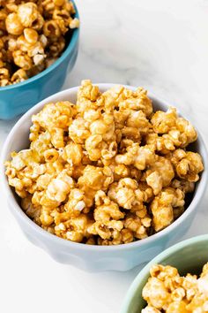 two bowls filled with popcorn sitting on top of a white counter next to each other