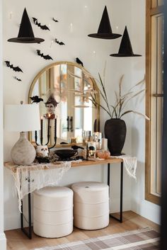 a table with two white stools under a mirror and bats on the wall above it