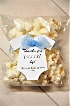 a bag of popcorn with a blue bow on it that says thanks for poppin'day