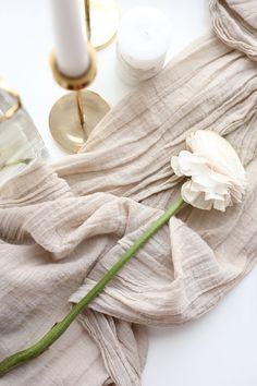 a white flower sitting on top of a table next to some candles and napkins