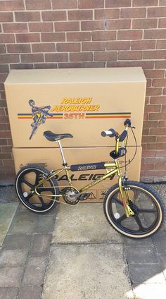 a golden bicycle parked next to a cardboard box