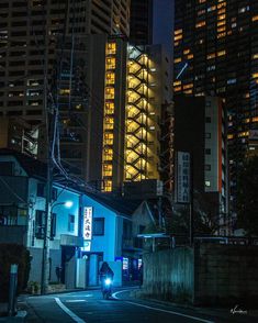 a city street at night with tall buildings in the background