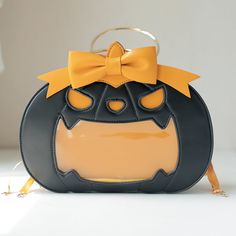 a black and orange purse with a yellow bow on it's head, sitting on a white surface