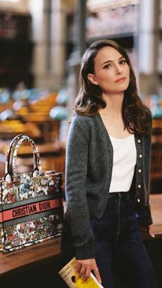 a woman sitting on a bench with a handbag in front of her and another purse behind her