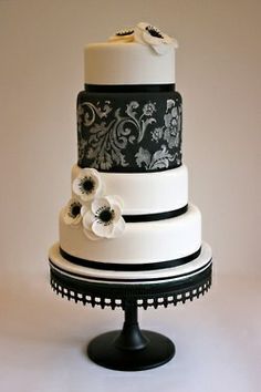 a three tiered wedding cake with black and white designs on it's sides