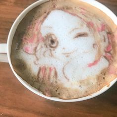 a coffee cup with a drawing of a girl on the foam in it's cappuccino