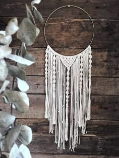 a white dream catcher hanging on a wooden wall