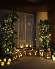 candles are lit in front of the letters that spell out marry me and roses on them