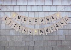 a welcome little muggie banner hanging on the side of a brick building in front of a wooden wall