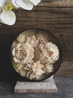 white flowers are in a bowl on a table