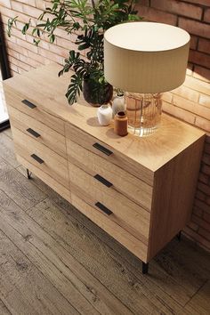 a wooden dresser sitting next to a brick wall with a lamp on top of it