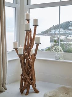 a candle holder made out of driftwood in front of a window