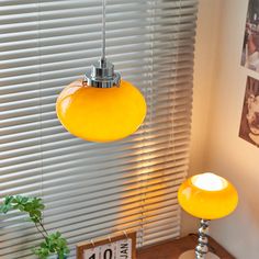 a yellow lamp hanging over a table next to a window