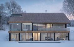 a modern house in the snow with lots of windows and sliding doors on each side