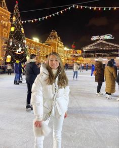 a woman is standing in the middle of an ice rink at night with christmas lights