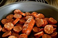 cooked sausages in a frying pan on top of the stove burner, ready to be eaten