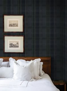 two framed pictures hang above a bed with white linens and pillows on the headboard