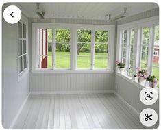 an empty room with white walls and wood flooring is shown in this image, there are flowers on the window sill