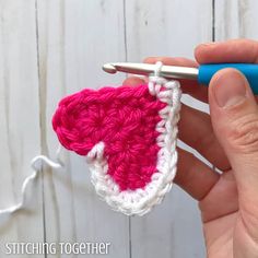 the crochet heart is being worked on by someone using a knitting needle to make it