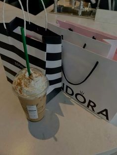 a cup of coffee sitting on top of a table next to two bags with handles