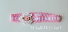 a pink and white crocheted headband with a flower